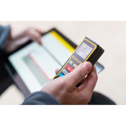STANLEY STHT1-77343 laser distance measurer held in hand, display lit, digital photography.