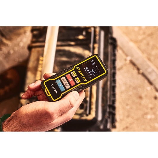 STANLEY STHT1-77343 laser distance measurer, black and yellow, held in hand, close-up view.