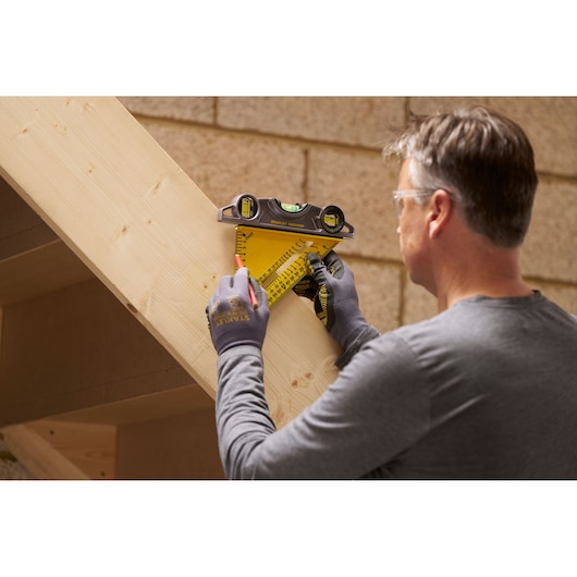 STANLEY STHT46012-0 rafter square with level used by person marking measurements on wooden beam.