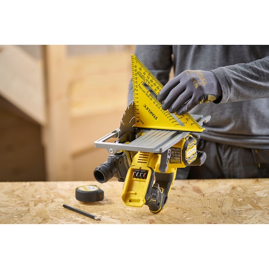 Stanley STHT46012-0 photography of yellow layout square used for measurement on a power saw, shown in workshop setting.