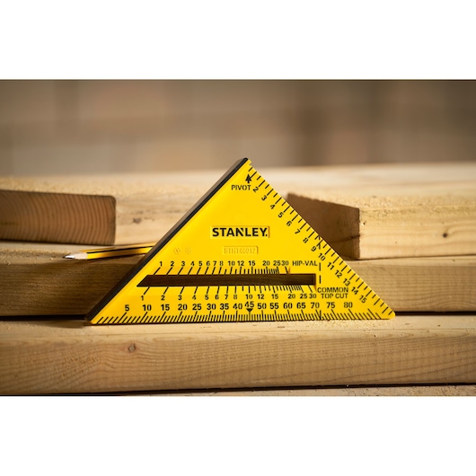 STANLEY STHT46012-0 yellow triangle carpenter square on wooden boards, side angle outdoor.