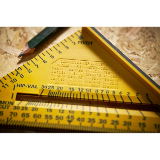 Photo of STANLEY STHT46012-0 yellow rafter square with conversion chart, close-up on wooden surface.