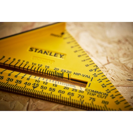 STANLEY STHT46012-0 yellow carpenter's square, close-up, showing scales and markings on wood surface.