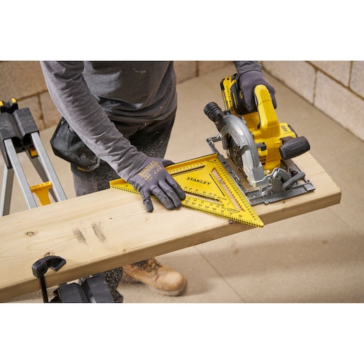 STANLEY STHT46013-0 yellow plastic rafter square used for marking wood in workshop setting.