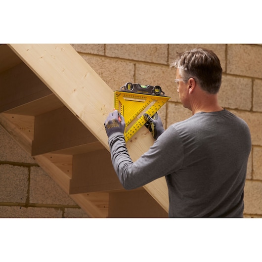STANLEY STHT46013-0 yellow layout square with built-in level used on wooden stairs construction.