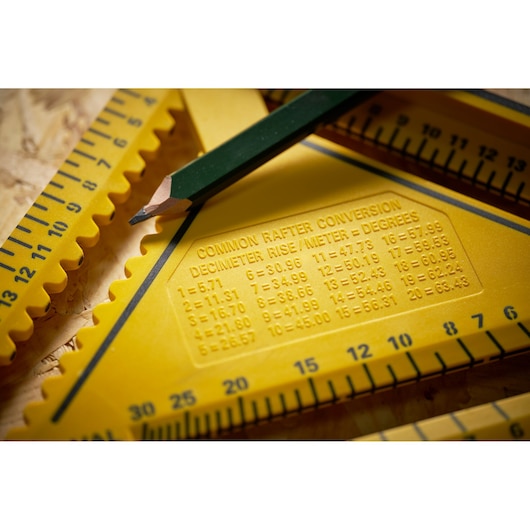 STANLEY STHT46013-0 yellow rafter square with conversion table and green pencil in close-up photography.