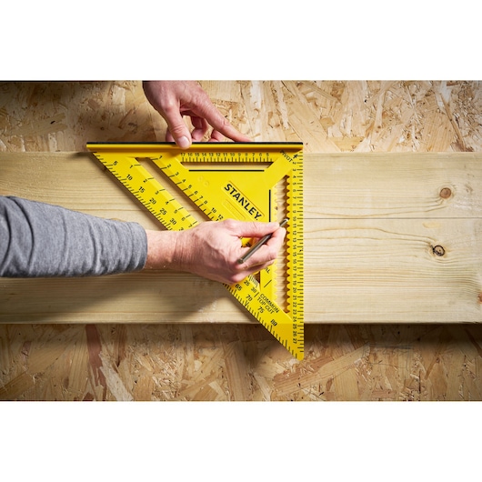 STANLEY STHT46013-0 yellow rafter square held against wooden plank, top view, photography.
