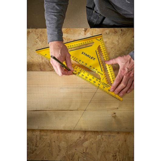 Photo of STANLEY STHT46013-0 yellow carpenter's square in use for marking wood on workbench.