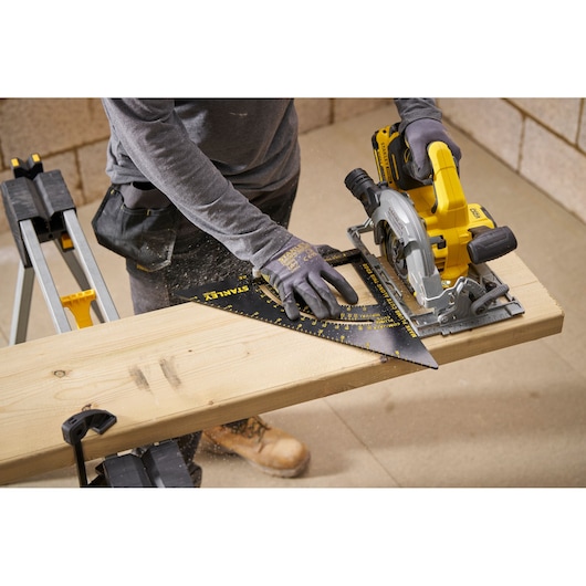 Photo of STANLEY STHT46054-0 square tool on wooden board, used by worker with circular saw in workshop.