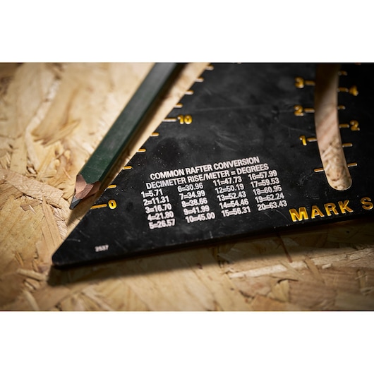 STANLEY STHT46054-0 photography of black rafter square with conversion table, close-up on wood surface.