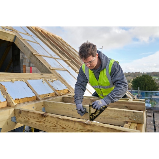 STANLEY STHT46056-0 roofing square held by worker measuring timber frame on construction site.
