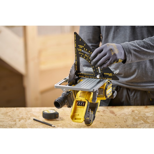 STANLEY STHT46056-0 rafter square in use, measuring saw angle, on a woodworking table with tape measure and pencil.