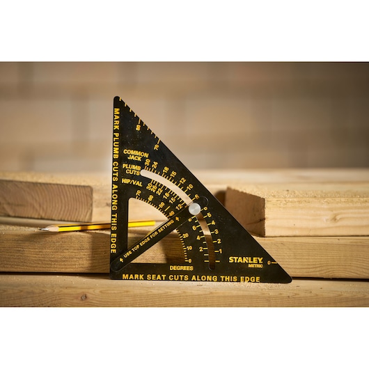 Stanley STHT46056-0 photography of black metric carpenter square with yellow markings on stacked wood.