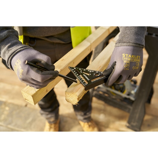 STANLEY STHT46100-0 rafter square used to measure and mark a wooden beam, worker wearing gloves.