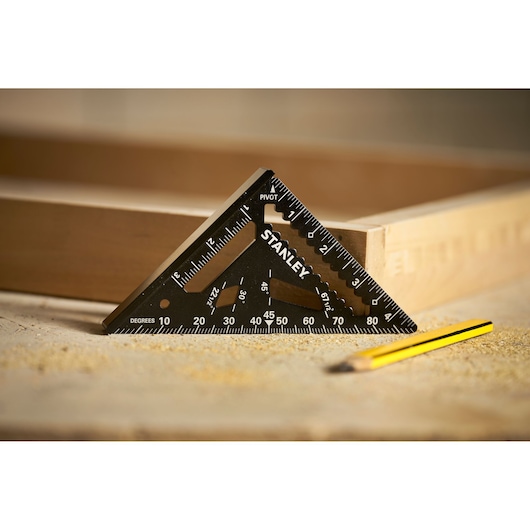 STANLEY STHT46103-0 black triangular carpenter’s square on work surface next to yellow pencil.