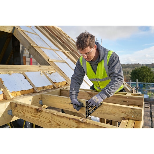 STANLEY STHT46104-0 roofing square tool in use on wooden beams at a construction site.