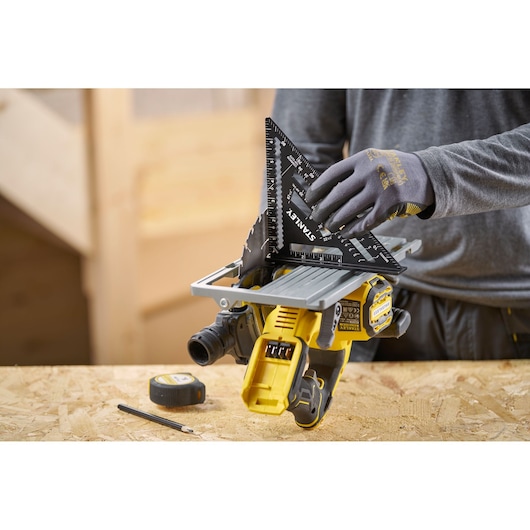 Photo of STANLEY STHT46104-0 black layout square held on a workbench next to a power tool, tape measure, and pencil.