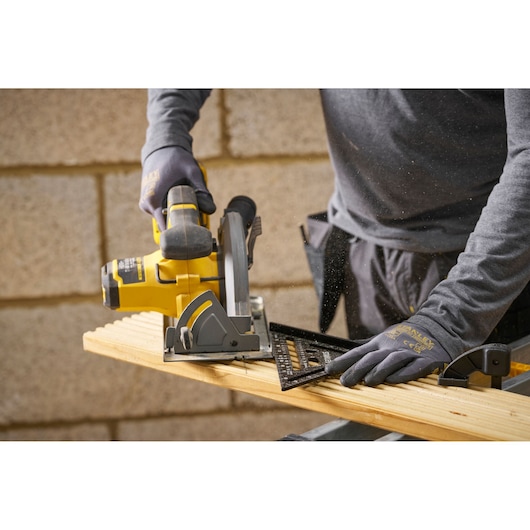STANLEY STHT46104-0 carpentry square in use, guiding a circular saw on a wooden board in workshop.