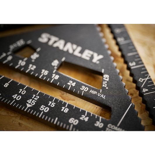 Photo of STANLEY STHT46104-0 black metal carpenter square with measurement markings, close-up angle.