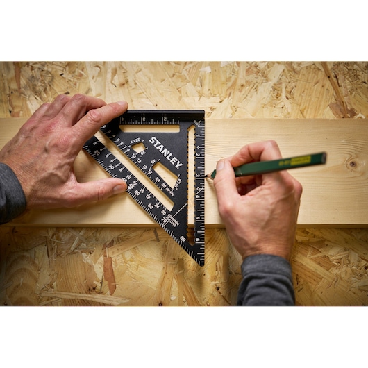 STANLEY STHT46104-0 black speed square used for marking lines on light wood, top view.
