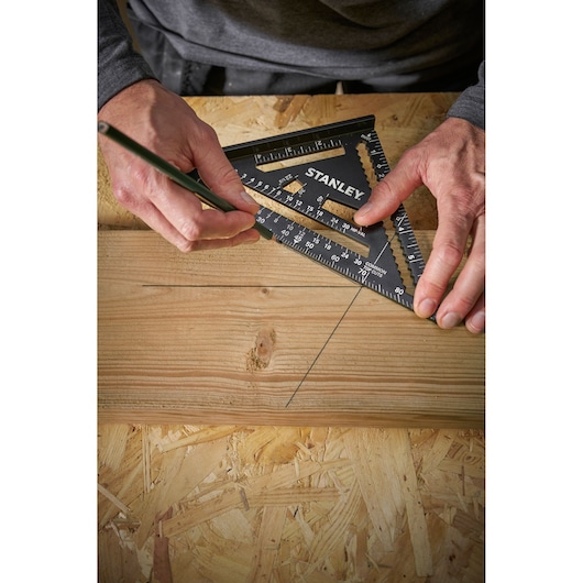 STANLEY STHT46104-0 black square ruler being used to mark a wooden board, top view.