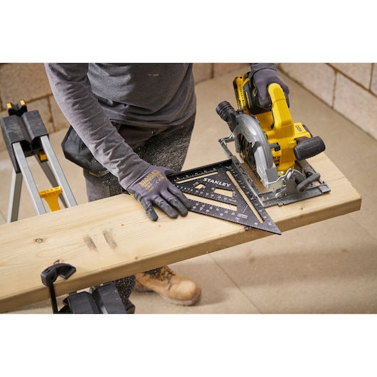 Photo of STANLEY STHT46105-0 carpenter's square on wood plank during cutting, workshop setting.