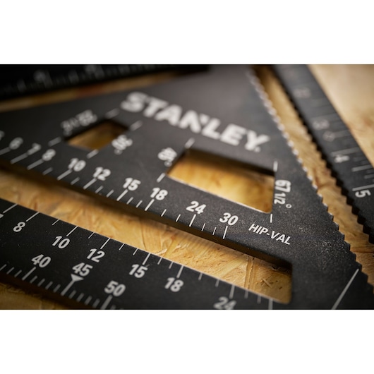 Photo of STANLEY STHT46105-0 black speed square with white markings on wood surface, close-up angle.