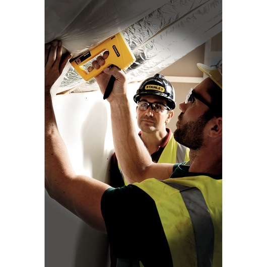 Photo of STANLEY STHT6-70409 staple gun in use by a worker installing insulation material.