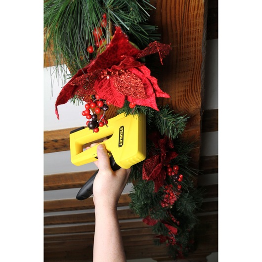 STANLEY STHT6-70409 staple gun held attaching Christmas garland with red flowers and berries.