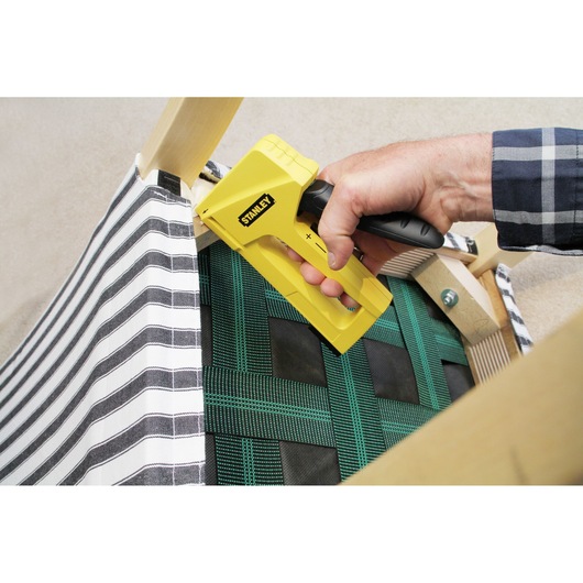 STANLEY STHT6-70409 stapler used on striped fabric upholstery, close-up angle.