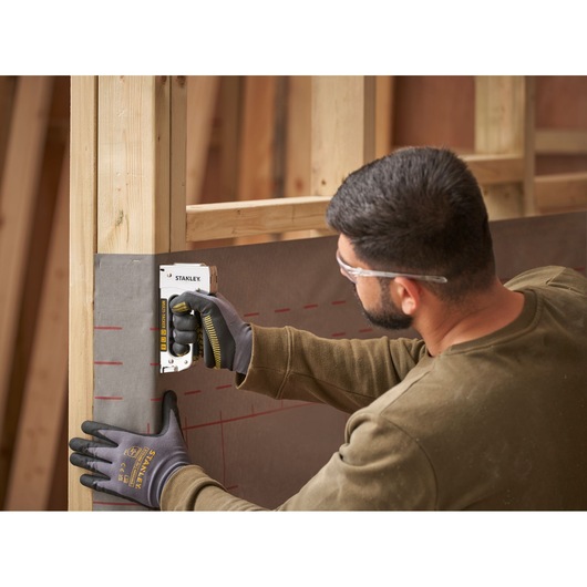 Stanley STHT6-70410 heavy-duty stapler used by person attaching material to wooden frame, construction context.