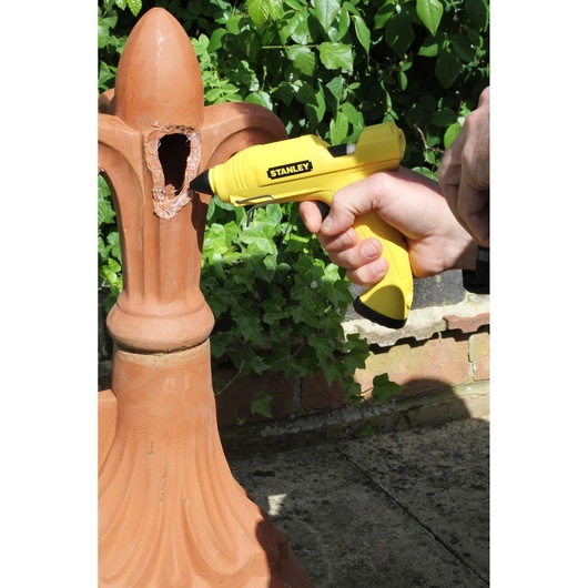 Stanley STHT6-70416 yellow glue gun used on damaged terracotta outdoors.