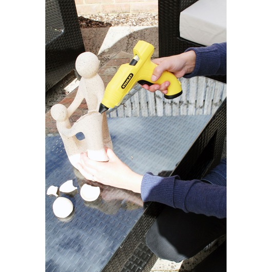 STANLEY STHT6-70416 photography of yellow glue gun used to repair stone sculpture on glass table.