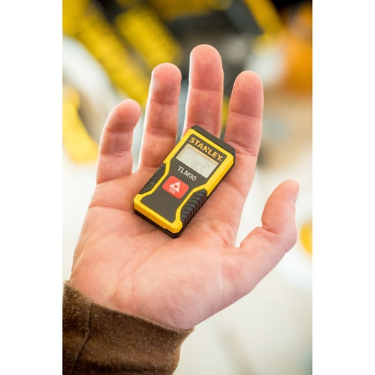 STANLEY STHT9-77425 compact yellow and black laser distance measurer held in a person's hand.