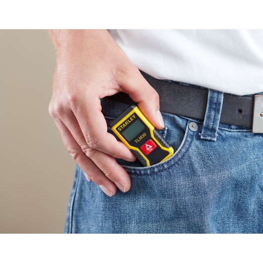 Photo of STANLEY STHT9-77425 laser measure held in hand, shown fitting in jeans pocket.