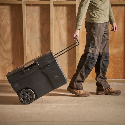 STANLEY STST1-70715 black wheeled toolbox being pulled by a person on a construction site.
