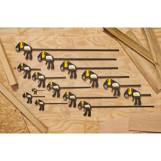 STANLEY FMHT83270-0 bar clamps set, various sizes, black and yellow, top-down view on wooden surface.